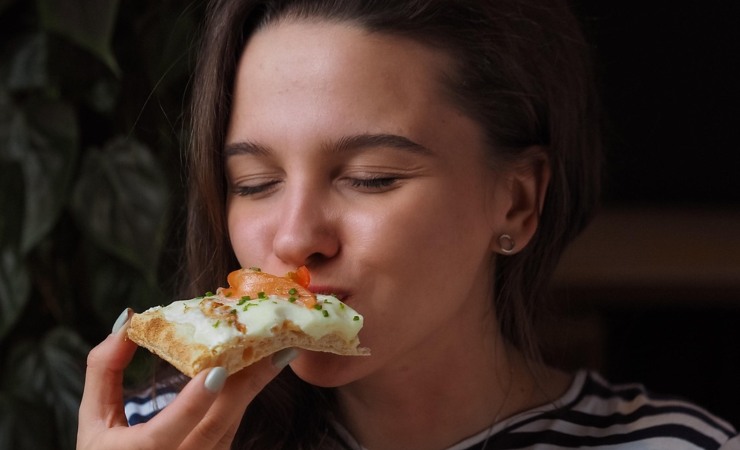 ragazza che mangia una fetta di pizza