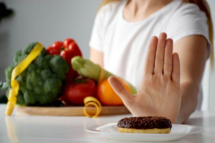 donna che fa segno di no al dolce con visino frutta e verdura