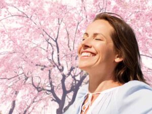 Donna sorridente, sullo sfondo un albero di ciliegio in fiore