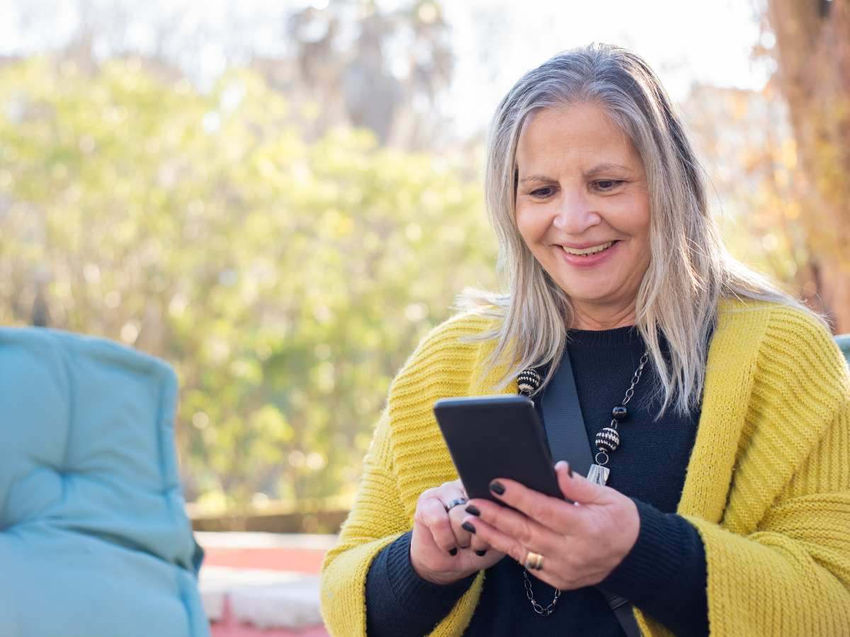 Donna anziana guarda lo smartphone sorridendo