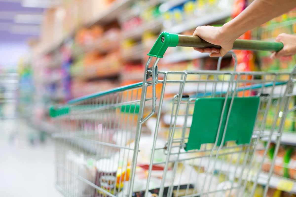 persona che spinge il carrello tra le corsie del supermercato