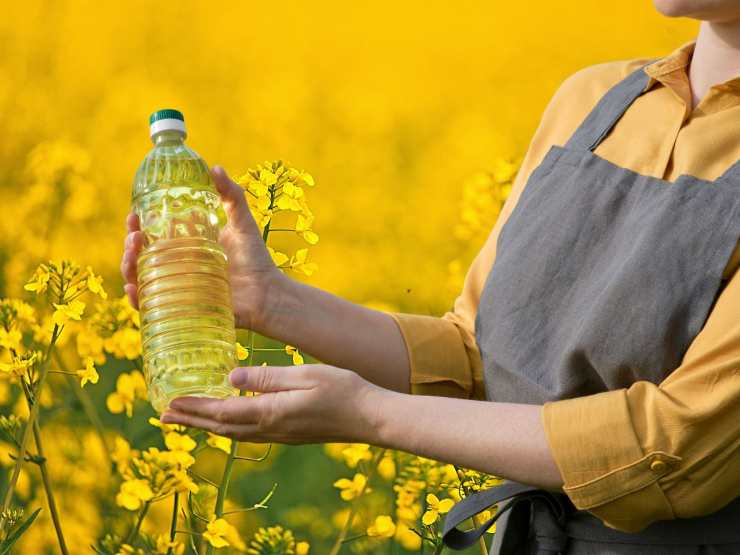 Donna con bottiglia olio e sfondo fiori 