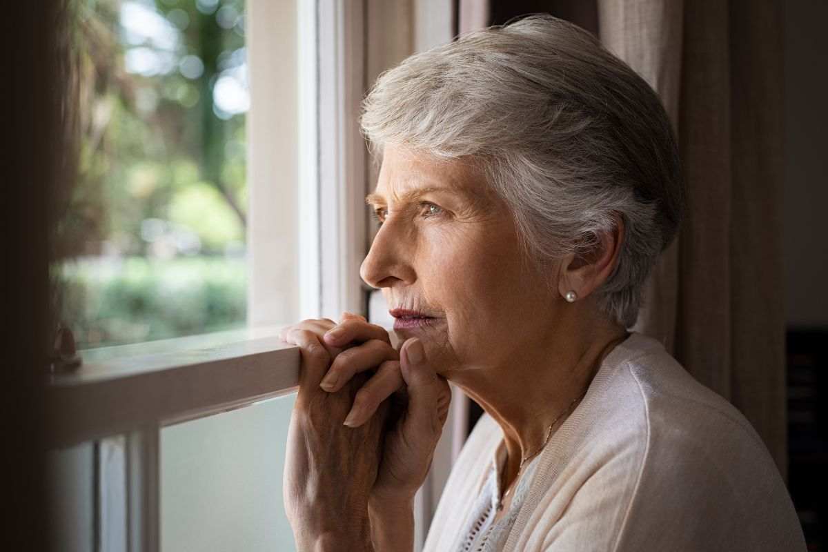 anziana con sguardo triste alla finestra